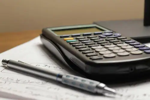 Calculator and pen on paper for construction project planning.