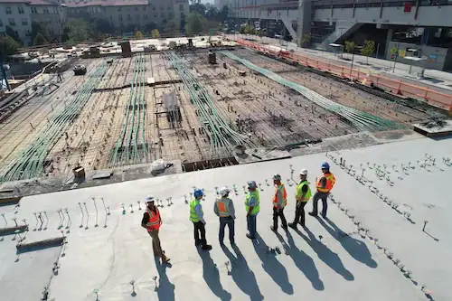 Construction workers inspecting a large building site with concrete and wiring.
